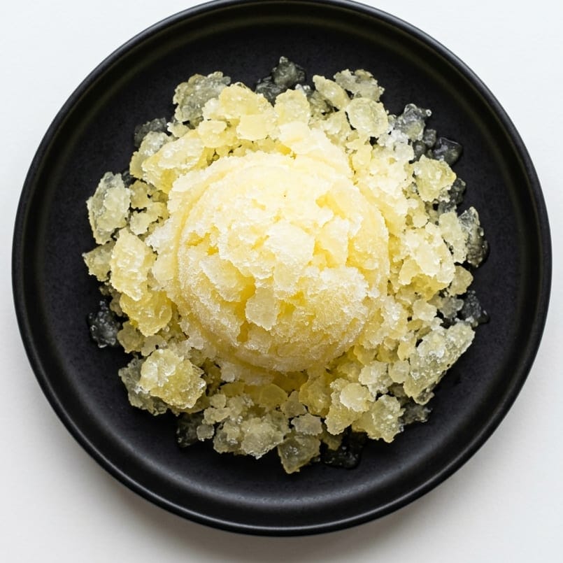 Yuzu granita in a black bowl, shaved ice around a pale yellow scoop