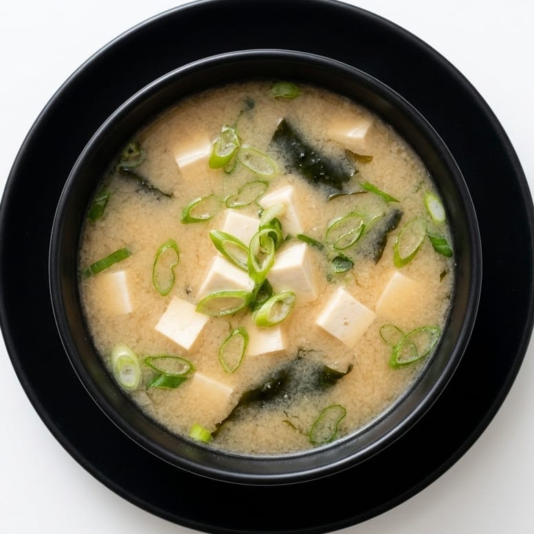 Miso soup in a black bowl, tofu, wakame and spring onion